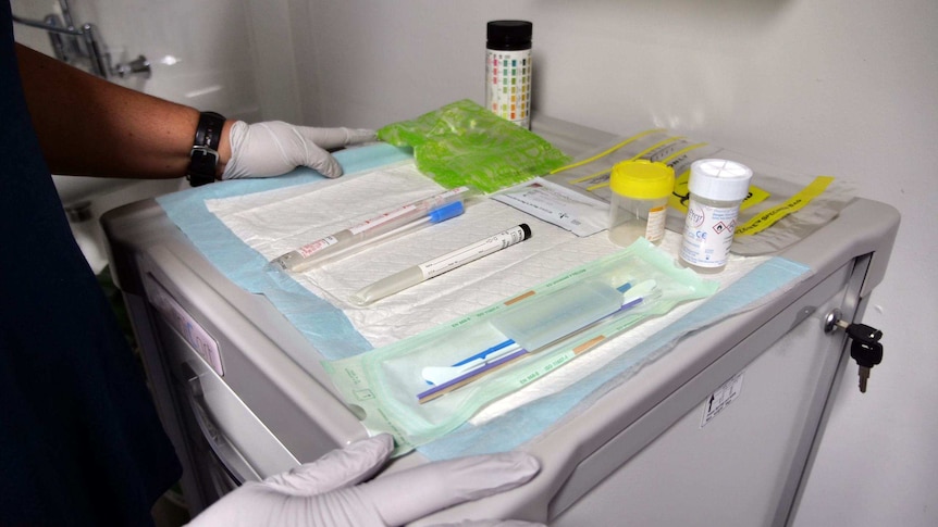 Swabs and sample collection containers laid out on a blue sheet in preparation for a cervical screening test