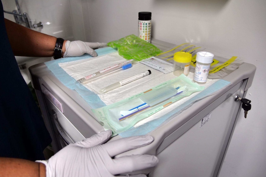 Swabs and sample collection containers laid out on a blue sheet in preparation for a cervical screening test