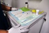 Swabs and sample collection containers laid out on a blue sheet in preparation for a cervical screening test