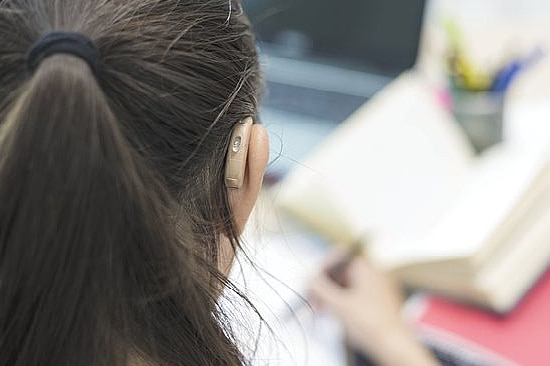 An image of the back of a young woman, who is wearing a hearing aid