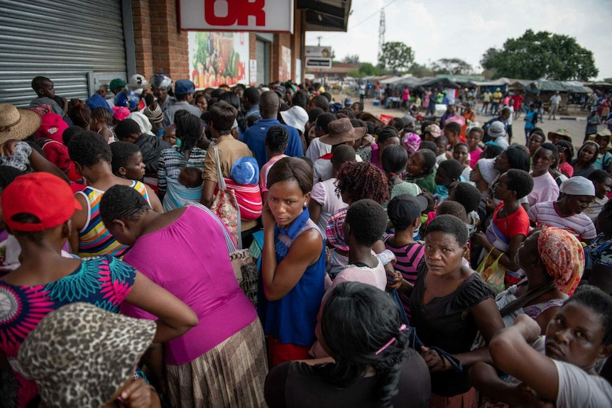 groups of people queue outside a shop