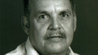 Headshot of a man wearing a white shirt against a black background.