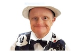 A man of small stature wearing a novelty waistcoat and a hat, smiling broadly.