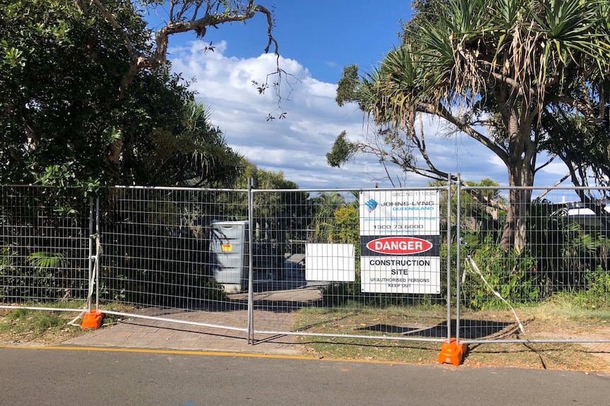 A fenced off construction site with warning signs