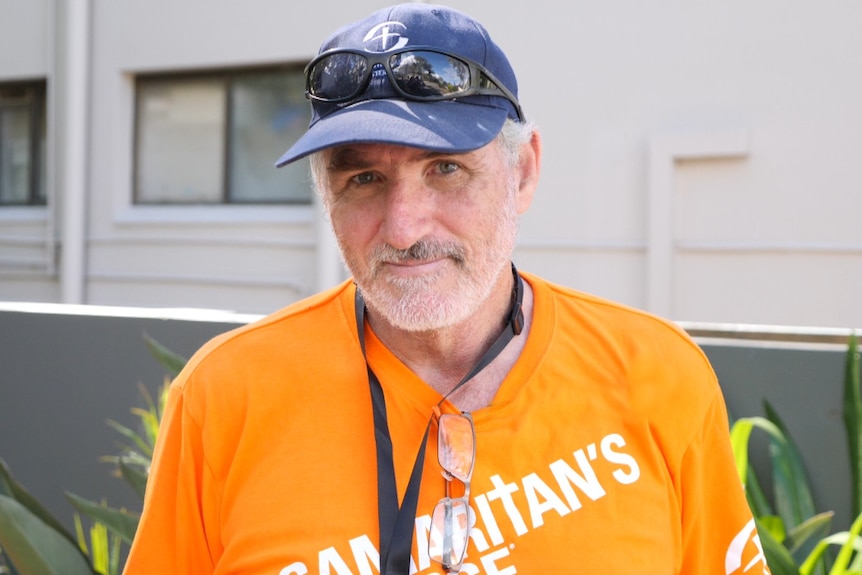 Man in cap with sunnies on top, orange Samaritan's Purse T-shirt, lanyard and glasses on neckline