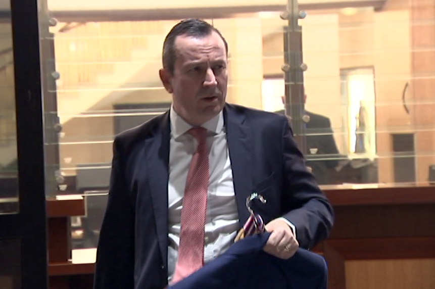 Mark McGowan carrying a suit and looking tired.