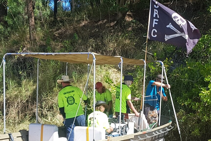 Members of the Jolly Roger's Fishing Club park their tinny along the Fitzroy River in Rockhampton looking for rubbish