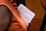 Woman in orange holds pile of papers 