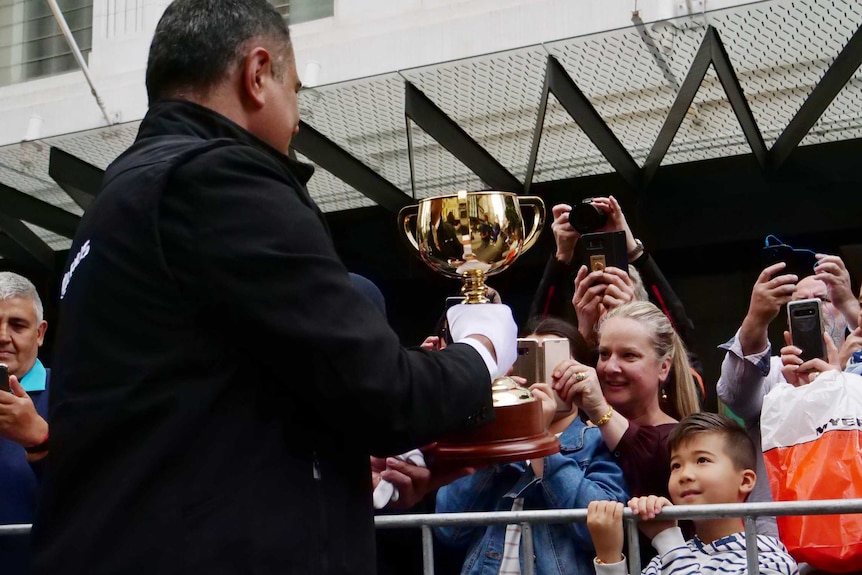 People at the Melbourne Cup parade taking photos of the trophy.