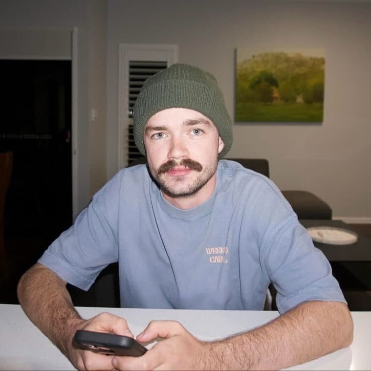 A man with his arms on a table wearing a beanie