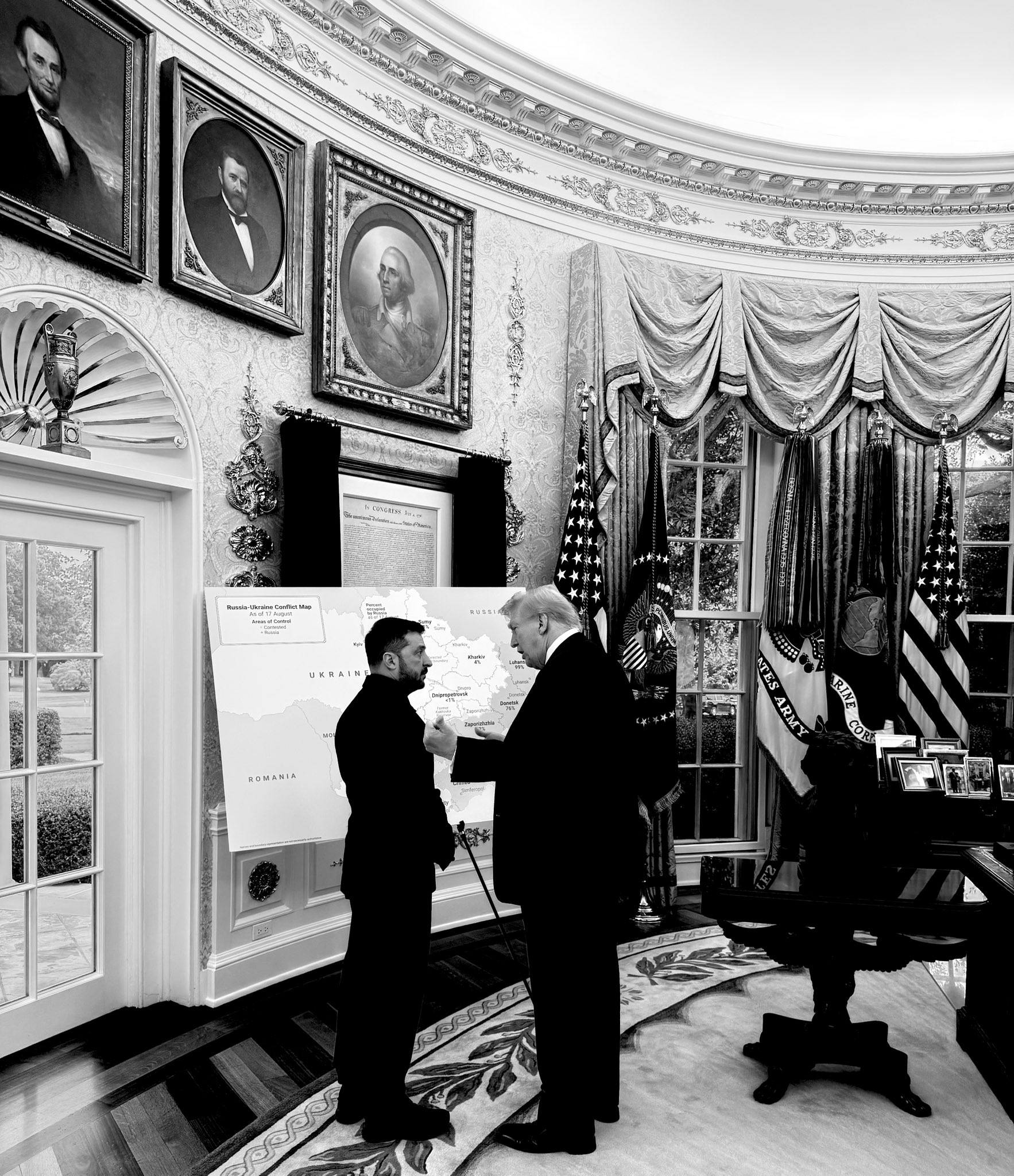 two men stand in a big room looking at a map
