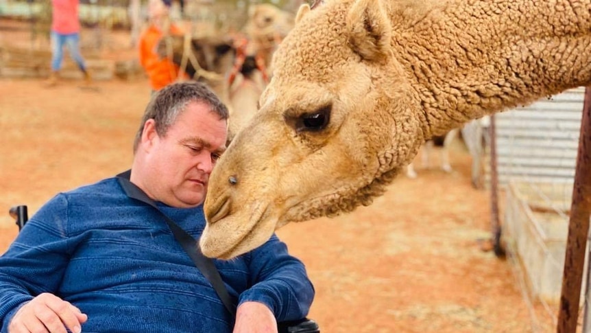 Tony from Live Better Broken Hill enjoying his time with a camel at Petah Devine's property
