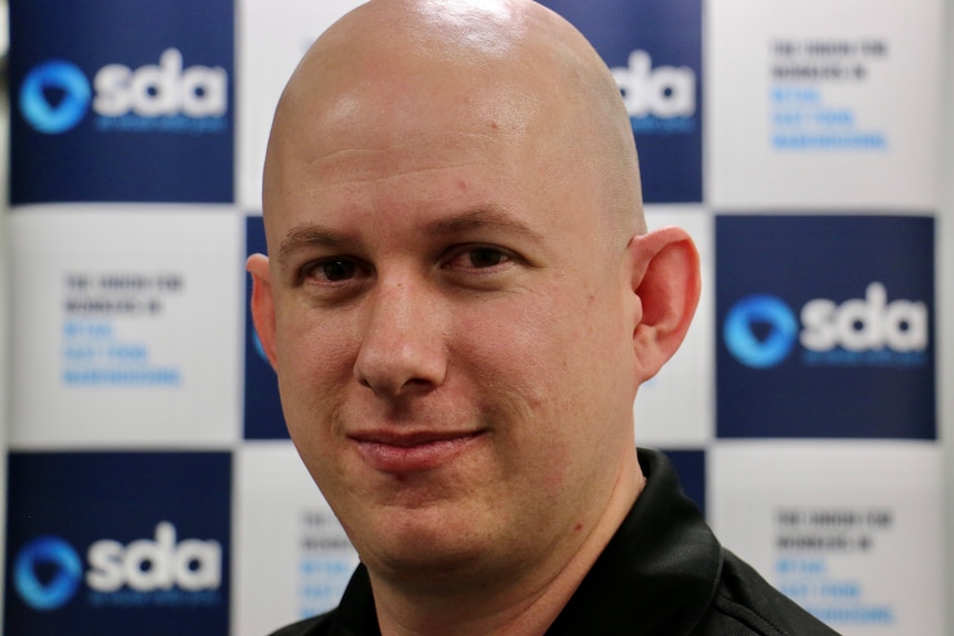 A close up shot of a bald man posing for a photo