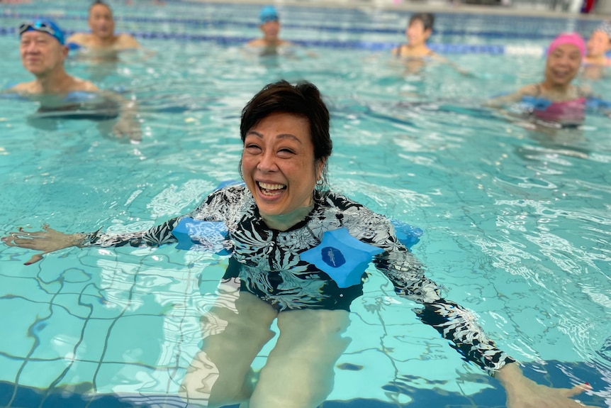 A smiling woman swimming in a pool.