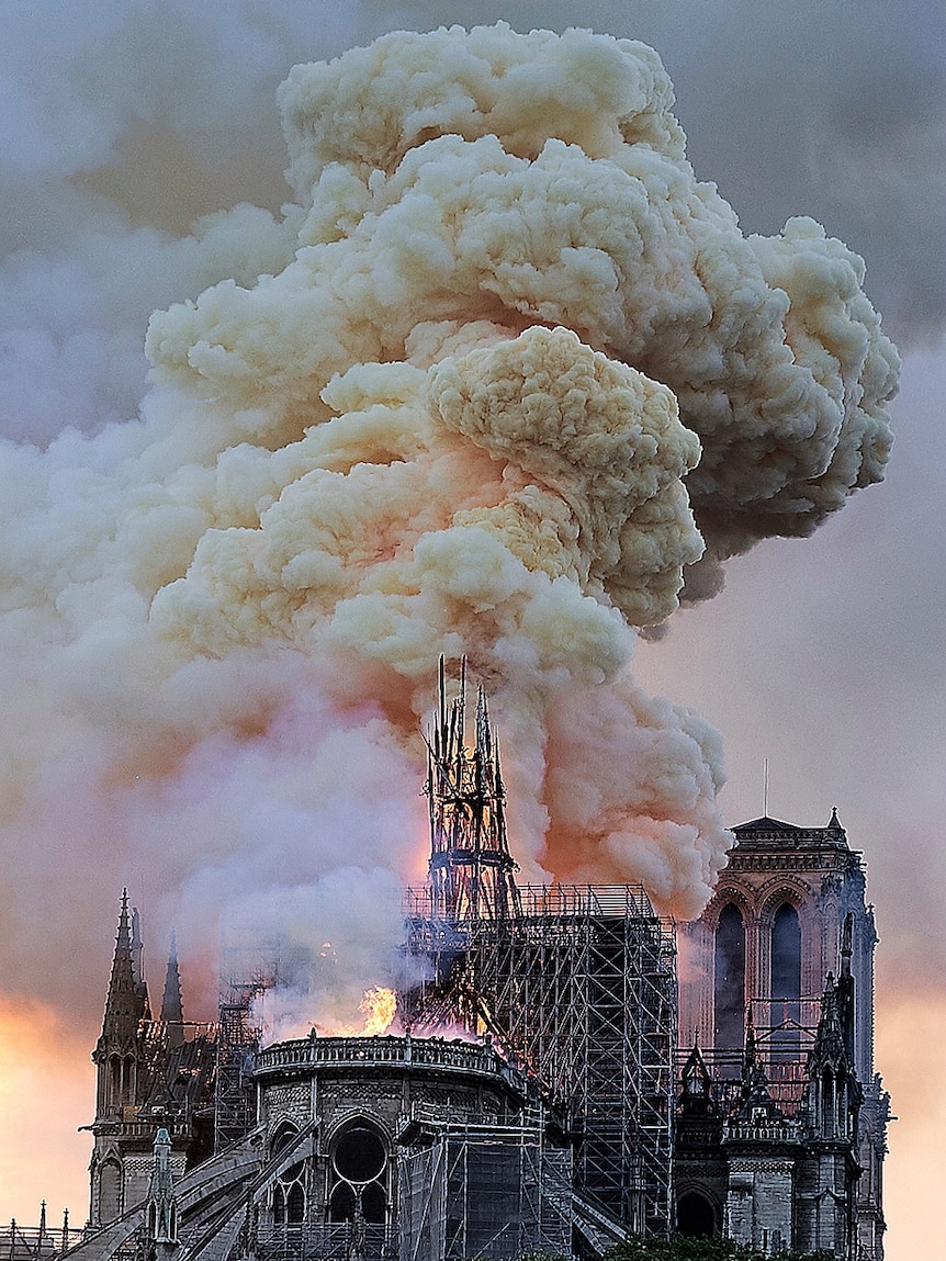 Flames and smoke rise as the spire on Notre Dame cathedral collapses.