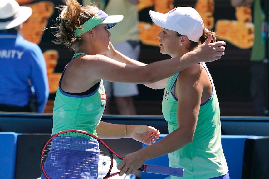 Two tennis players embrace at the net after an Australian Open match.