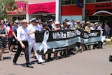 People marching behind White Ribbon banner in Darwin city.