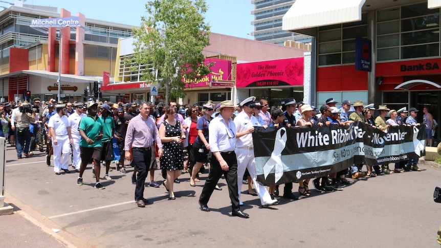 People marching behind White Ribbon banner in Darwin city.