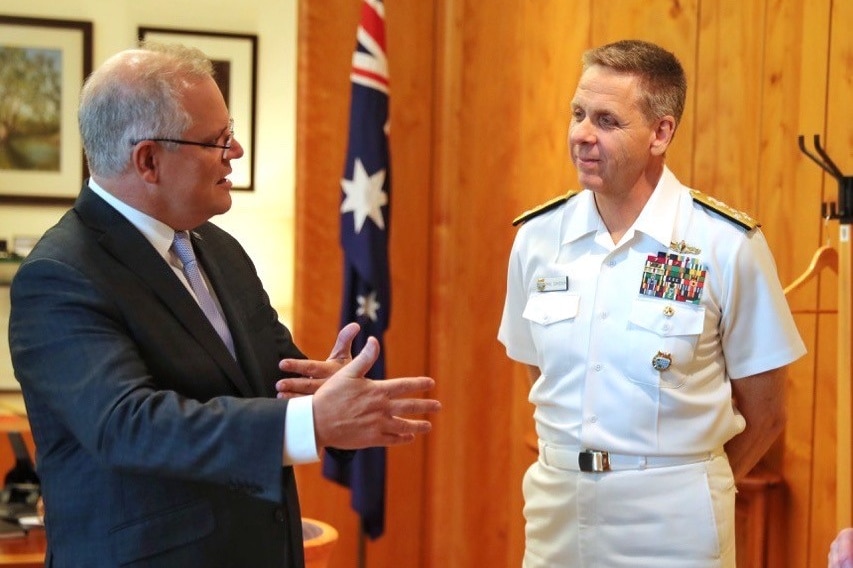 Prime Minister Scott Morrison is speaking to a man dressed in a white US navy uniform.
