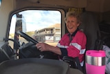 Woman laughing behind the wheel of a large vehicle. 