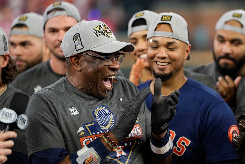 dusty baker smiles and claps his hands as he celebrates with his team