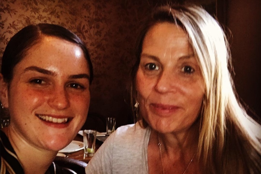 Two women - mother and daughter - smiling at a camera.