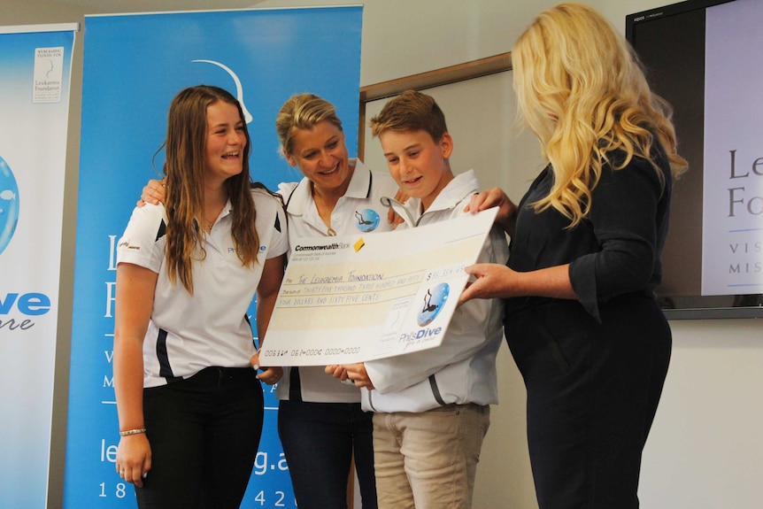A family presenting a large cheque to charity.