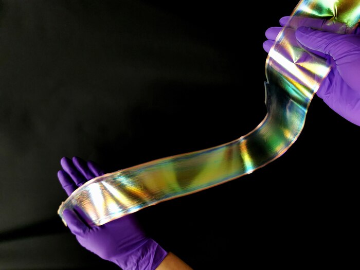 Two hands hold a strip of shimmering material