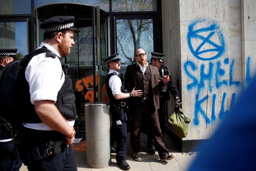 Police officers detain a climate change activist at the Shell Centre in London.