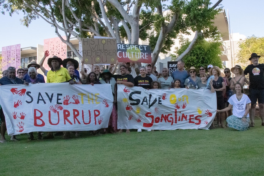 People standing on the grass,  holding up signs.