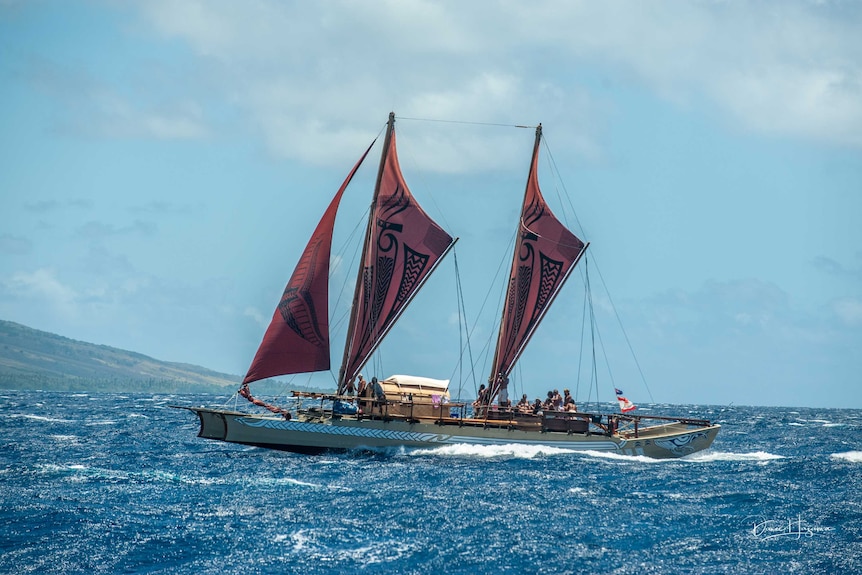 A sail boat with indigenous designs on its sails.