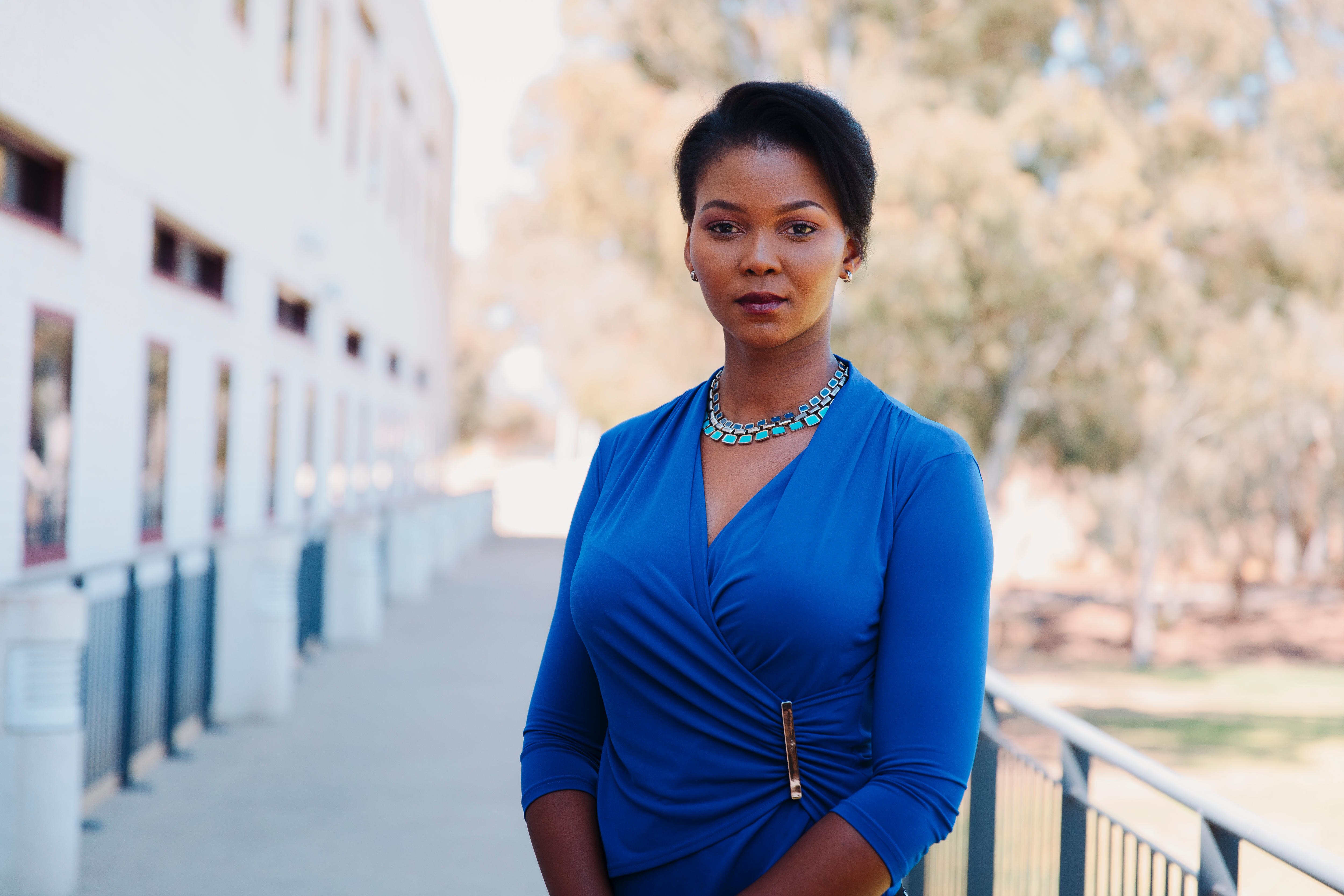 Dr Bomikazi Zeka stands facing the camera wearing a blue top