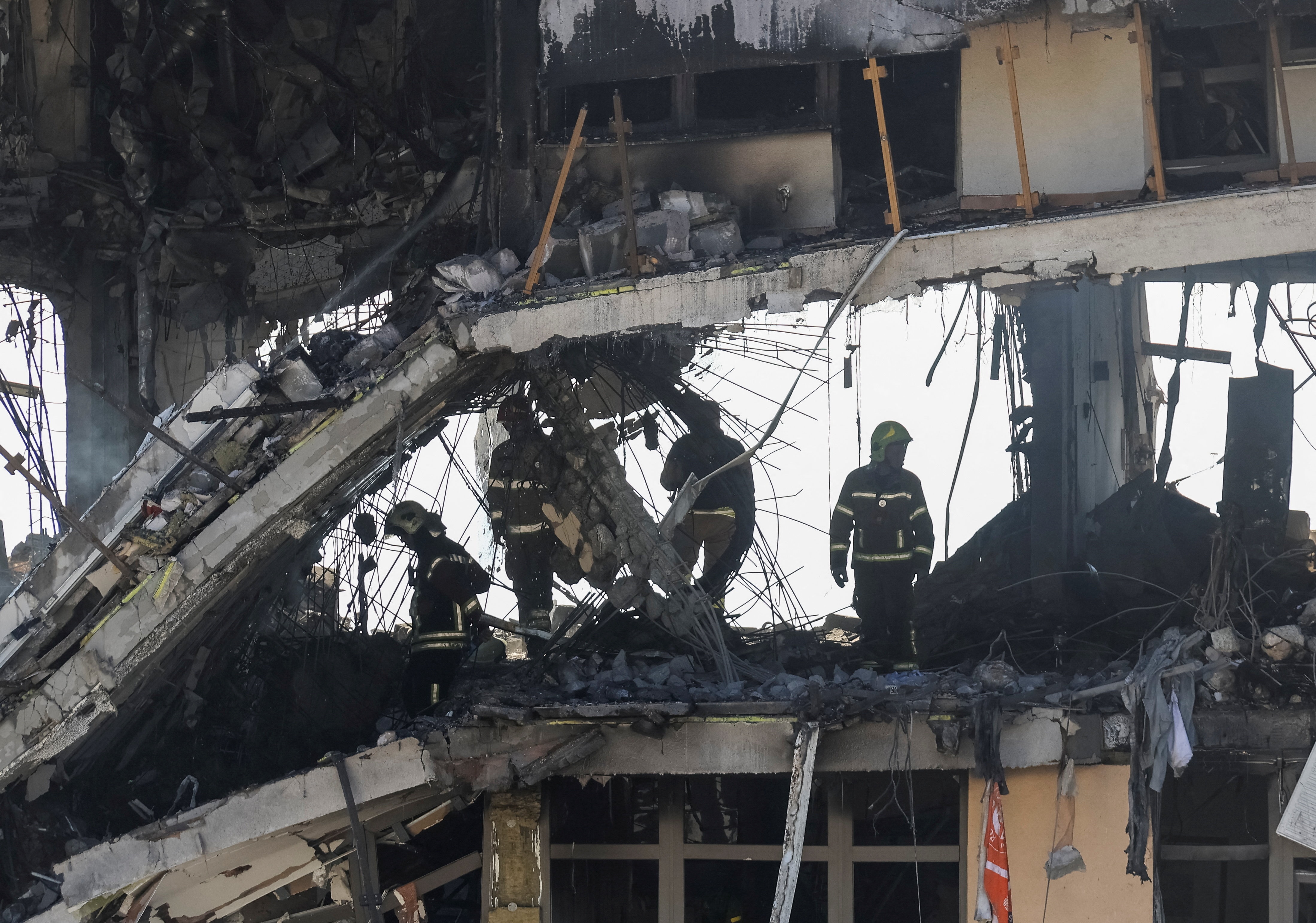A group of men inside shell of an apartment building destroyed by a drone strike