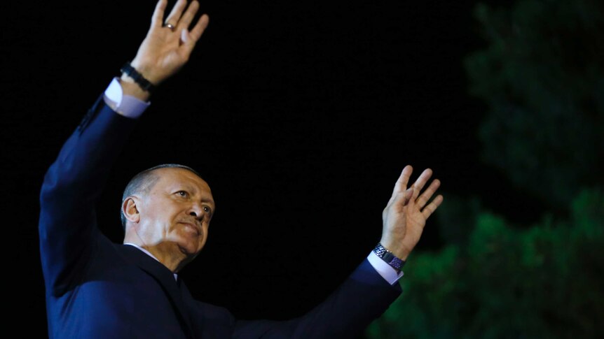 Recep Tayyip Erdogan holds both hands in the air as he acknowledges supporters.