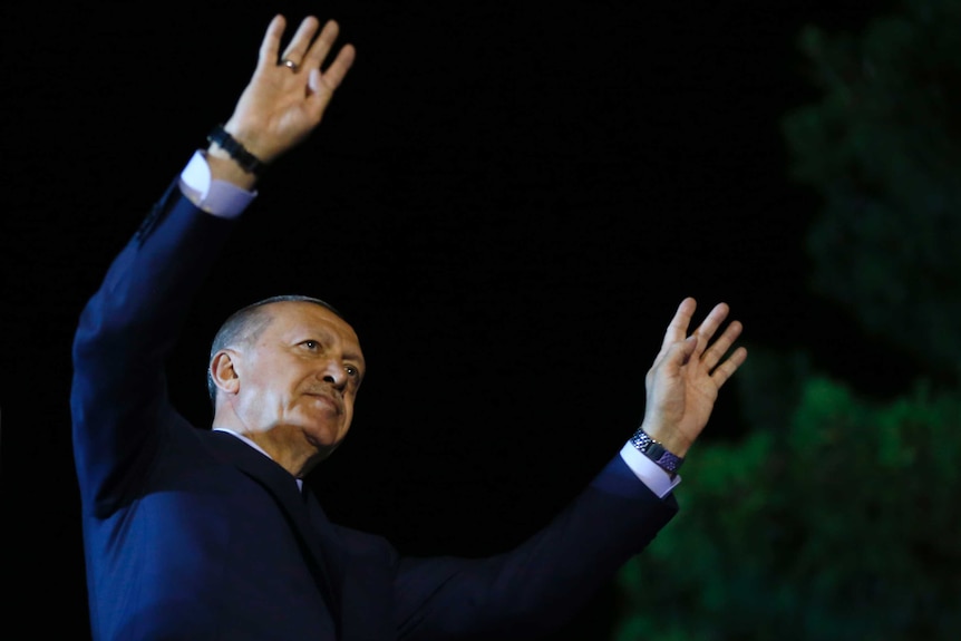 Recep Tayyip Erdogan holds both hands in the air as he acknowledges supporters.