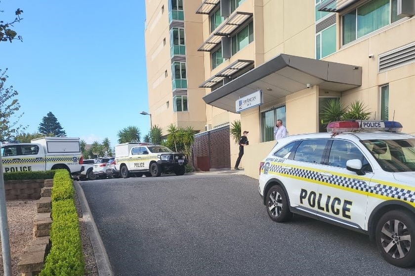 Three police vehicles parked outside a large hotel