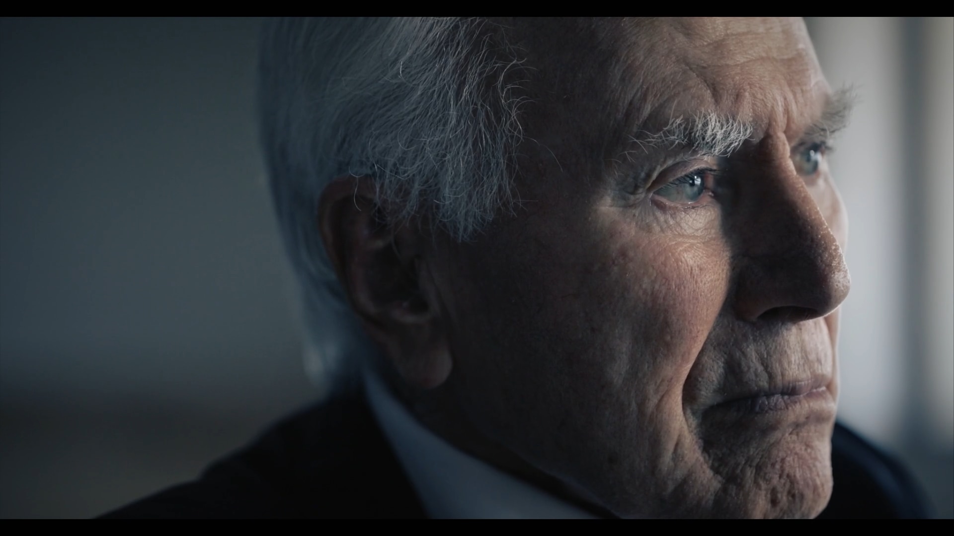 A close-up shot of an old man with thick white eyebrows looking thoughtfully off-camera.