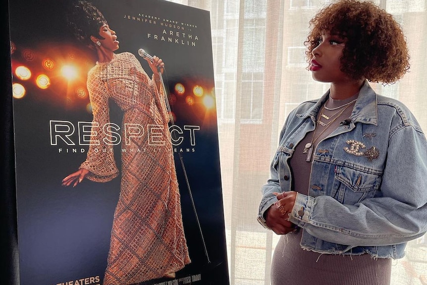 A woman looking at a poster of herself in a film.