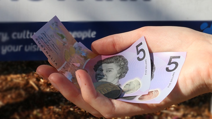 A hand holds money in Darwin.