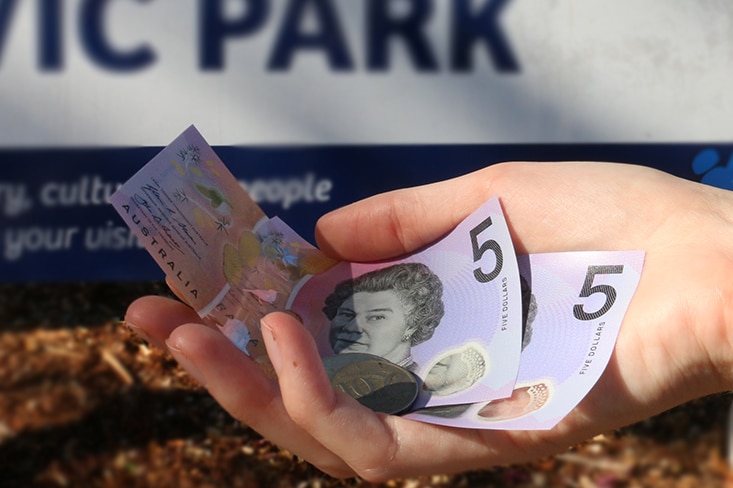 A hand holds money in Darwin.