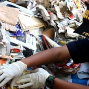 A customs officer standing in front of a giant pile of rubbish