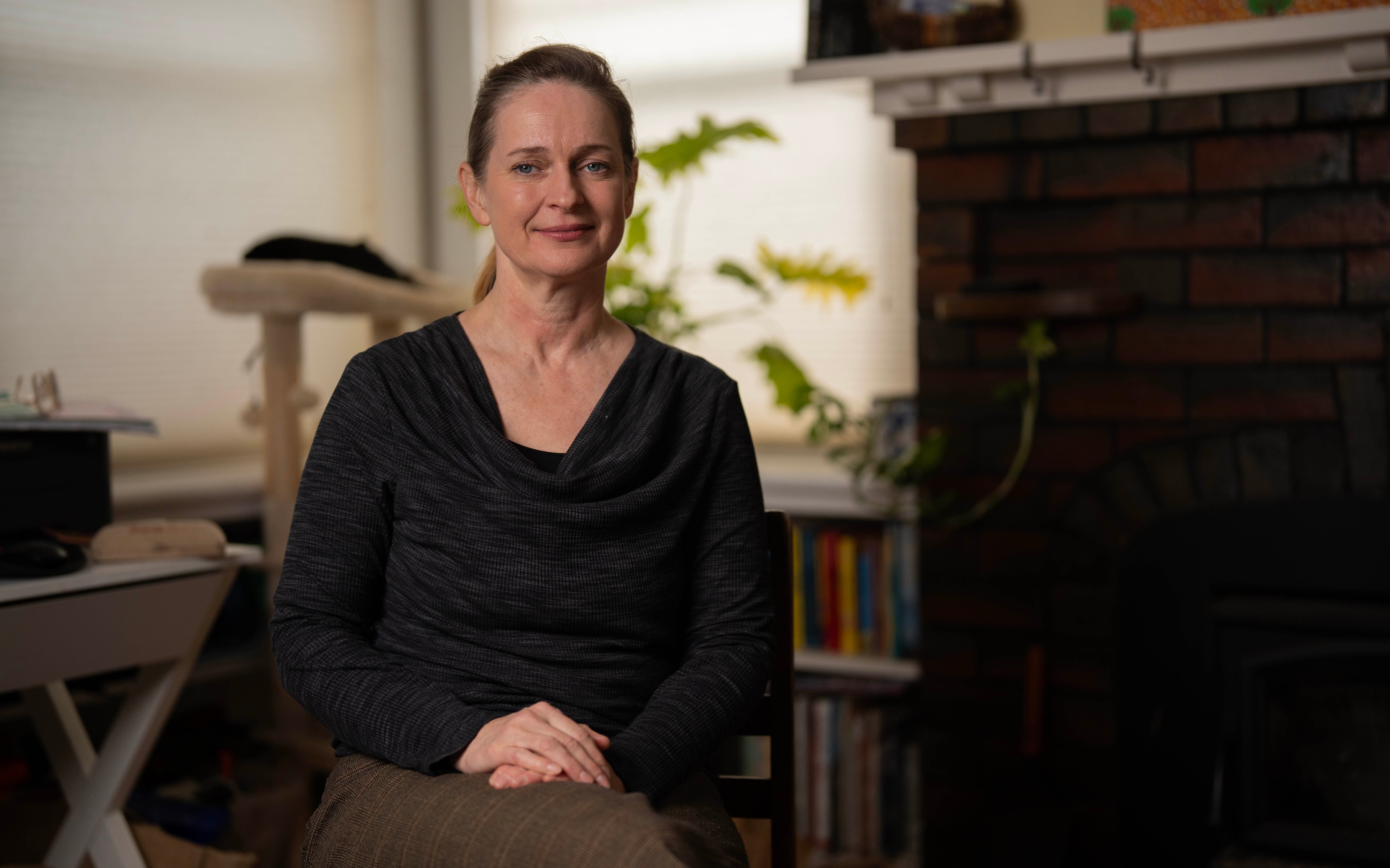A lady sitting on a chair in a living room, looking at the camera.