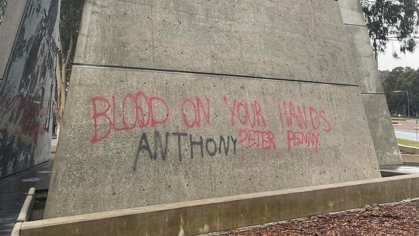 Red writing on concrete memorial. 