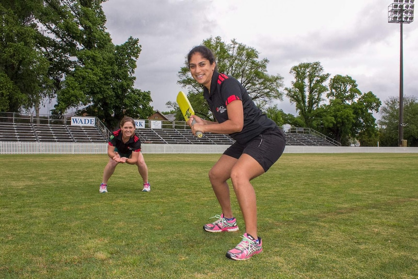 Two women wearing Australian Cricketers' Association uniforms in cricket poses