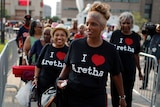 People with t-shirts saying "I love Aretha" wait in a line.