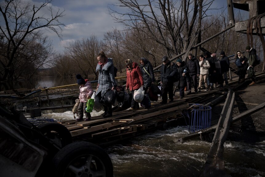 Ukrainians cross an improvised path under a destroyed bridge