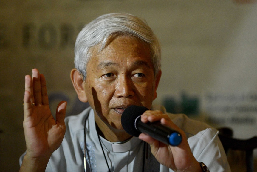 A man in religious dress speaks into a microphone.