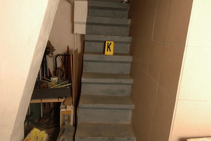 A police evidence label "K" sits on a narrow staircase.