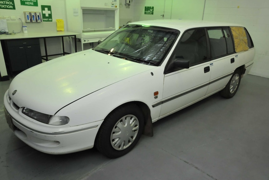 A white car parked in a room, which appears to be some kind of lab.