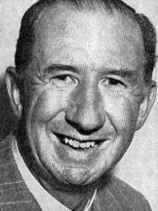 A grainy black and white photo of Nevil Shute, who has small dark eyes and a wide smile